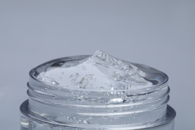 Jar of transparent cosmetic gel on light background, closeup