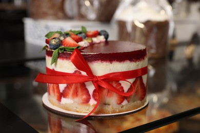 Photo of Delicious cake with strawberries on counter in bakery shop, closeup