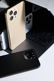 Photo of Modern laptop and smartphones on white table, closeup