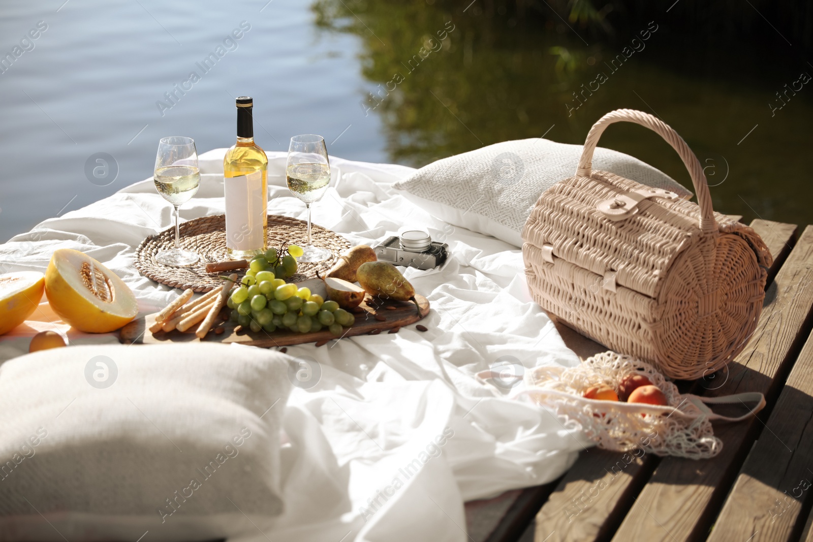 Photo of Picnic blanket with delicious food and wine on pier