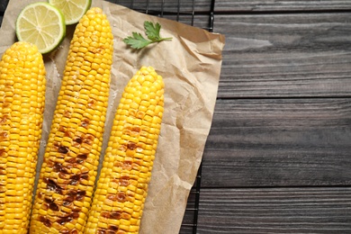 Photo of Tasty grilled corn on wooden table, flat lay. Space for text