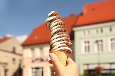 Woman holding delicious ice cream cone in city, closeup