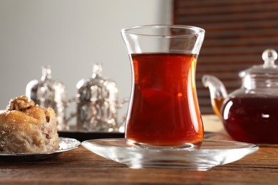 Photo of Turkish tea and sweets served in vintage tea set on wooden table, closeup