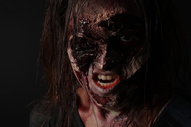 Photo of Scary zombie on dark background, closeup. Halloween monster