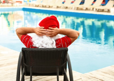 Photo of Authentic Santa Claus resting on lounge chair near pool at resort, back view