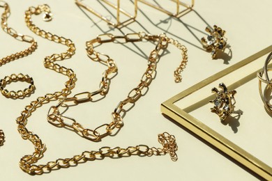 Photo of Metal chains and other different accessories on beige background. Luxury jewelry