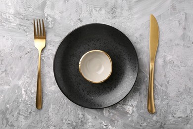 Elegant setting with golden cutlery on grey textured table, flat lay