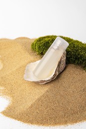 Photo of Bottle of serum and moss on sand against white background. Cosmetic product