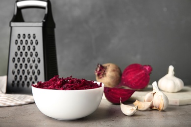 Photo of Bowl of grated fresh beets and garlic on table