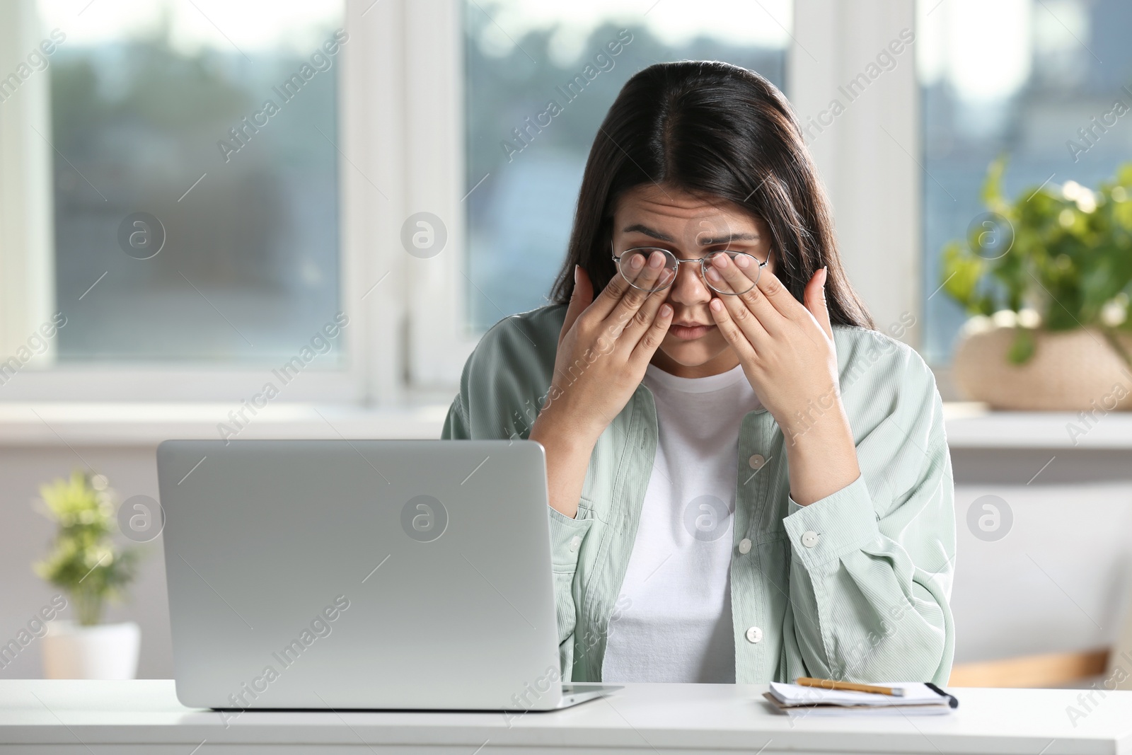 Photo of Young woman suffering from eyestrain at desk in office