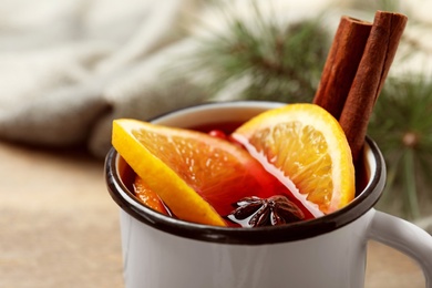 Photo of Mug with aromatic mulled wine on wooden table, closeup