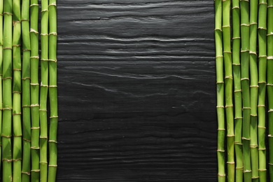 Green bamboo stems and space for text on wooden background, top view