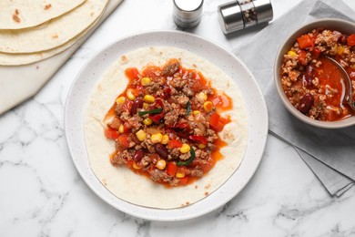 Photo of Tasty chili con carne with tortilla on white marble table, flat lay