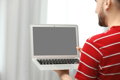 Young man using video chat on laptop indoors, closeup. Space for design