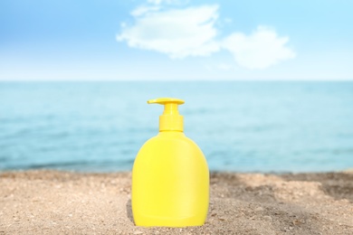 Photo of Bottle of sun protection body cream on beach, space for design