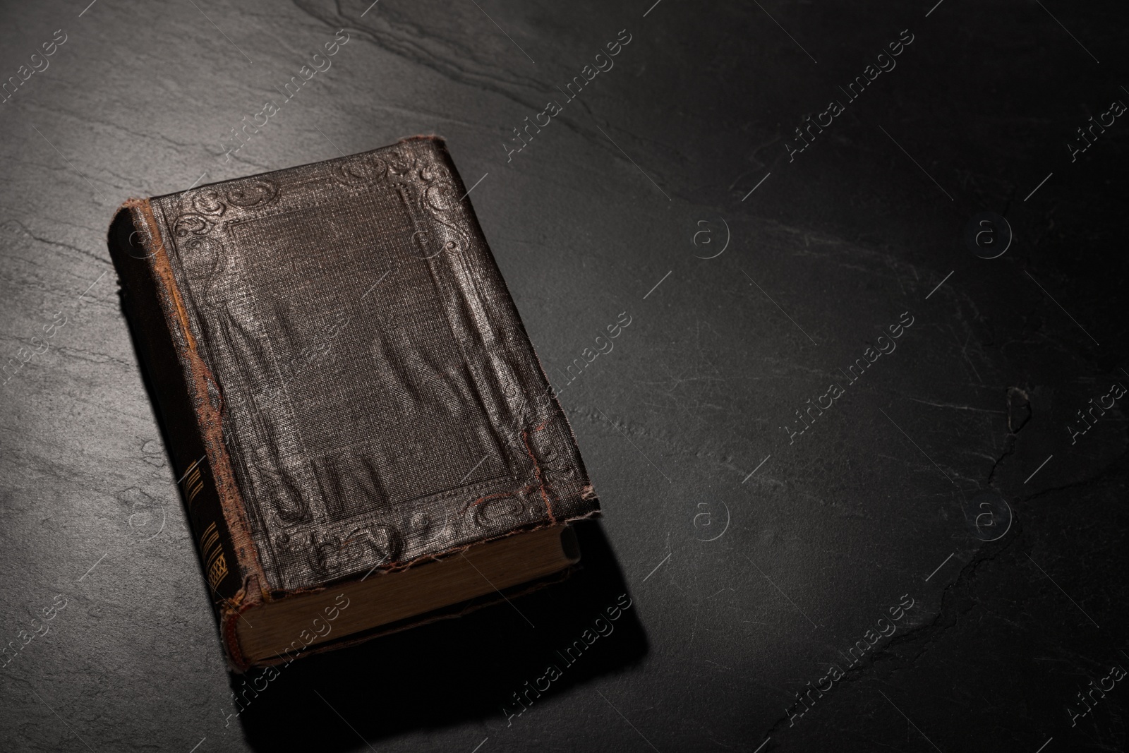 Photo of Old hardcover book on black textured table, space for text