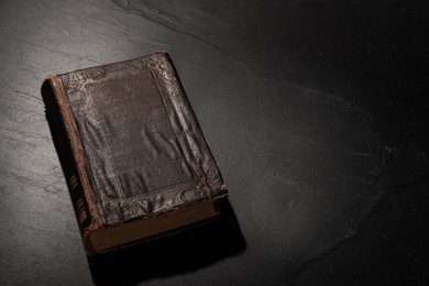 Old hardcover book on black textured table, space for text