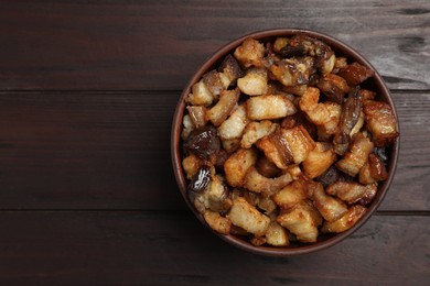 Tasty fried cracklings in bowl on wooden table, top view with space for text. Cooked pork lard