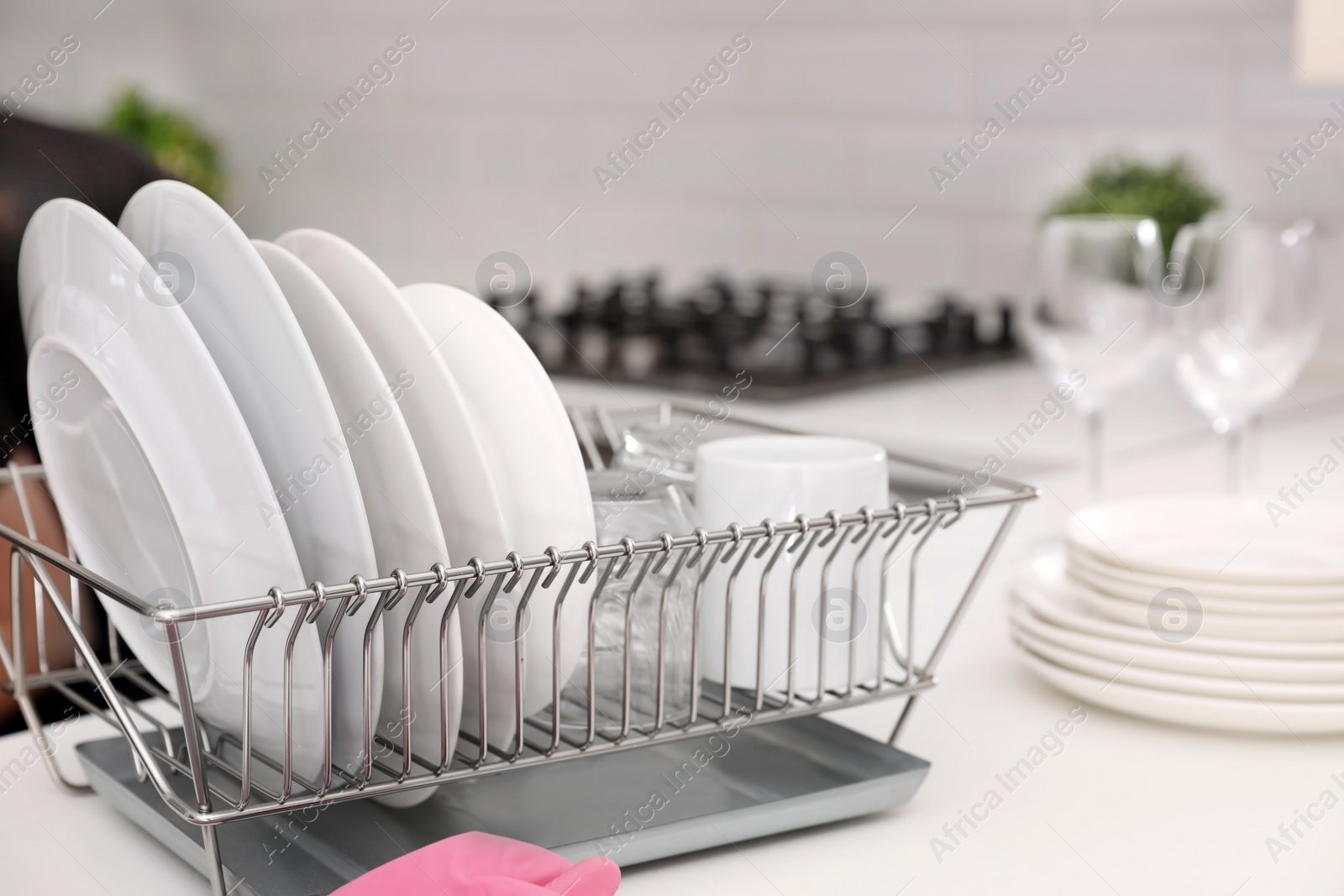 Photo of Dish drainer with clean dinnerware on table in kitchen