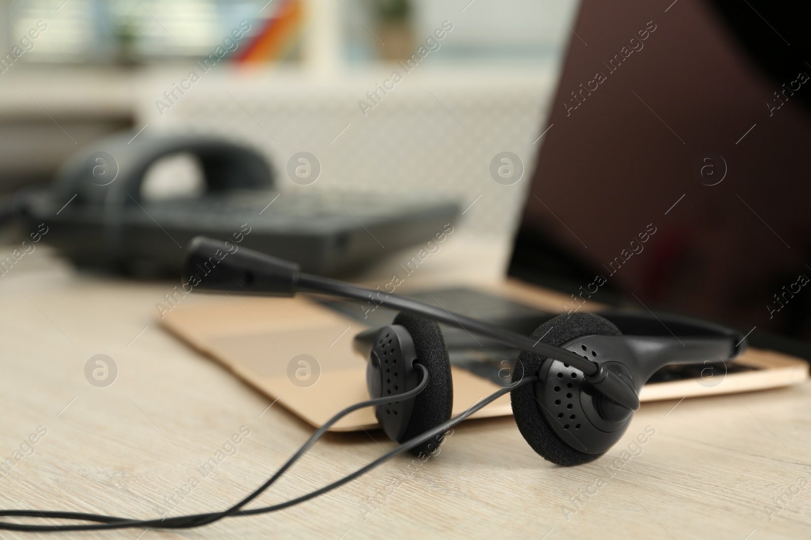 Photo of Headset and laptop on table indoors, closeup. Hotline concept