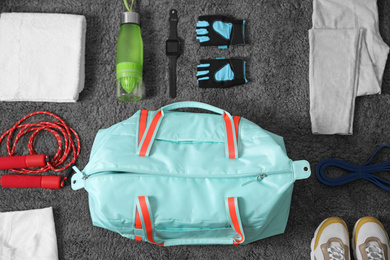 Photo of Flat lay composition with bag and sports items on grey carpet