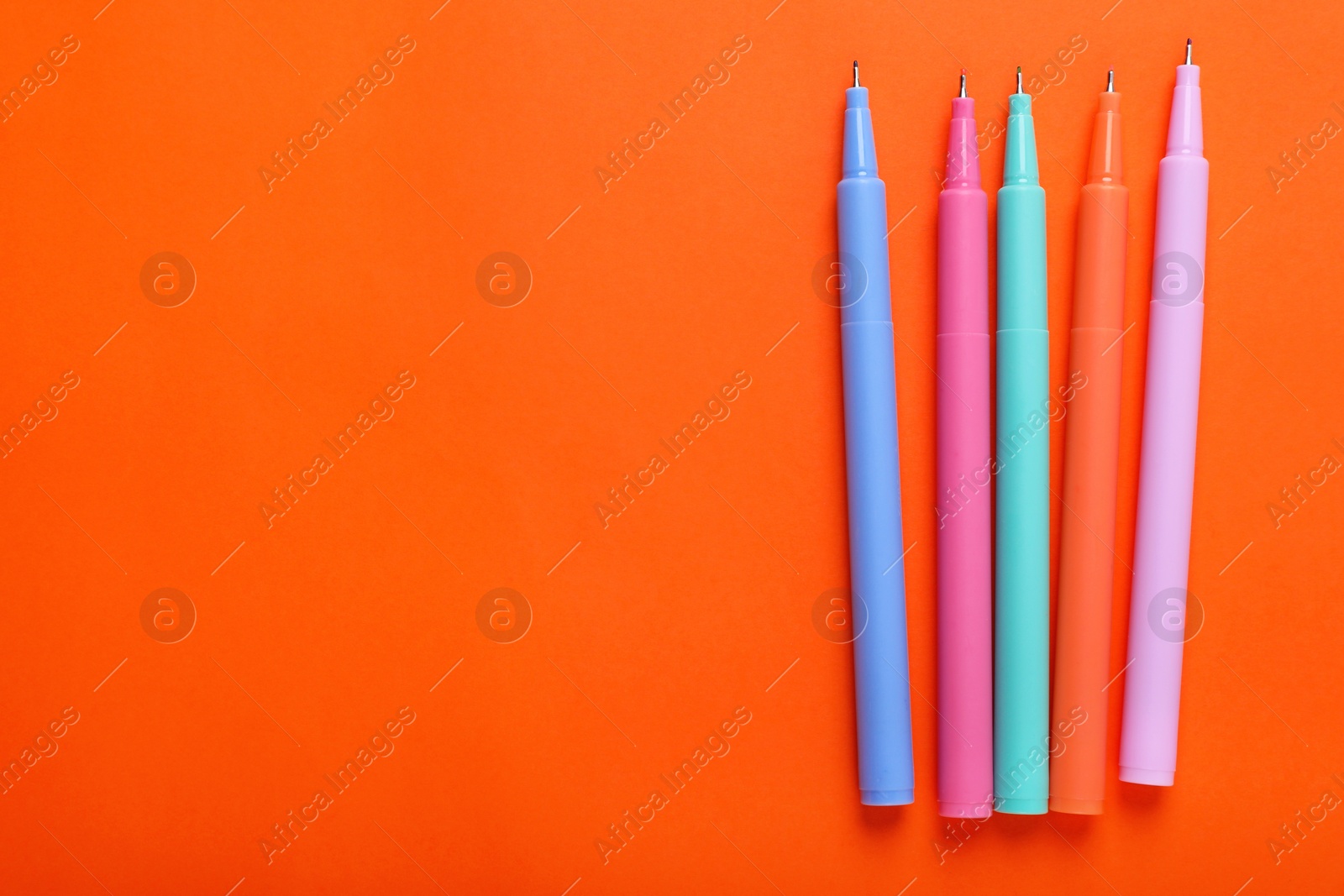Photo of Many colorful markers on orange background, flat lay. Space for text