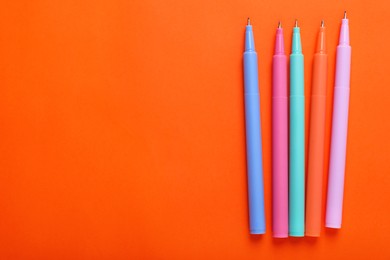 Photo of Many colorful markers on orange background, flat lay. Space for text