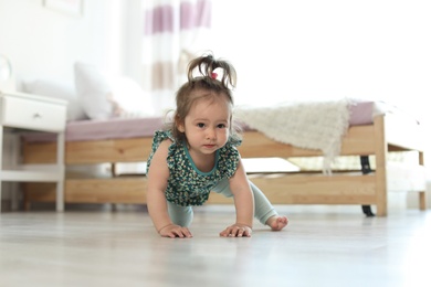 Adorable little baby girl crawling on floor in room