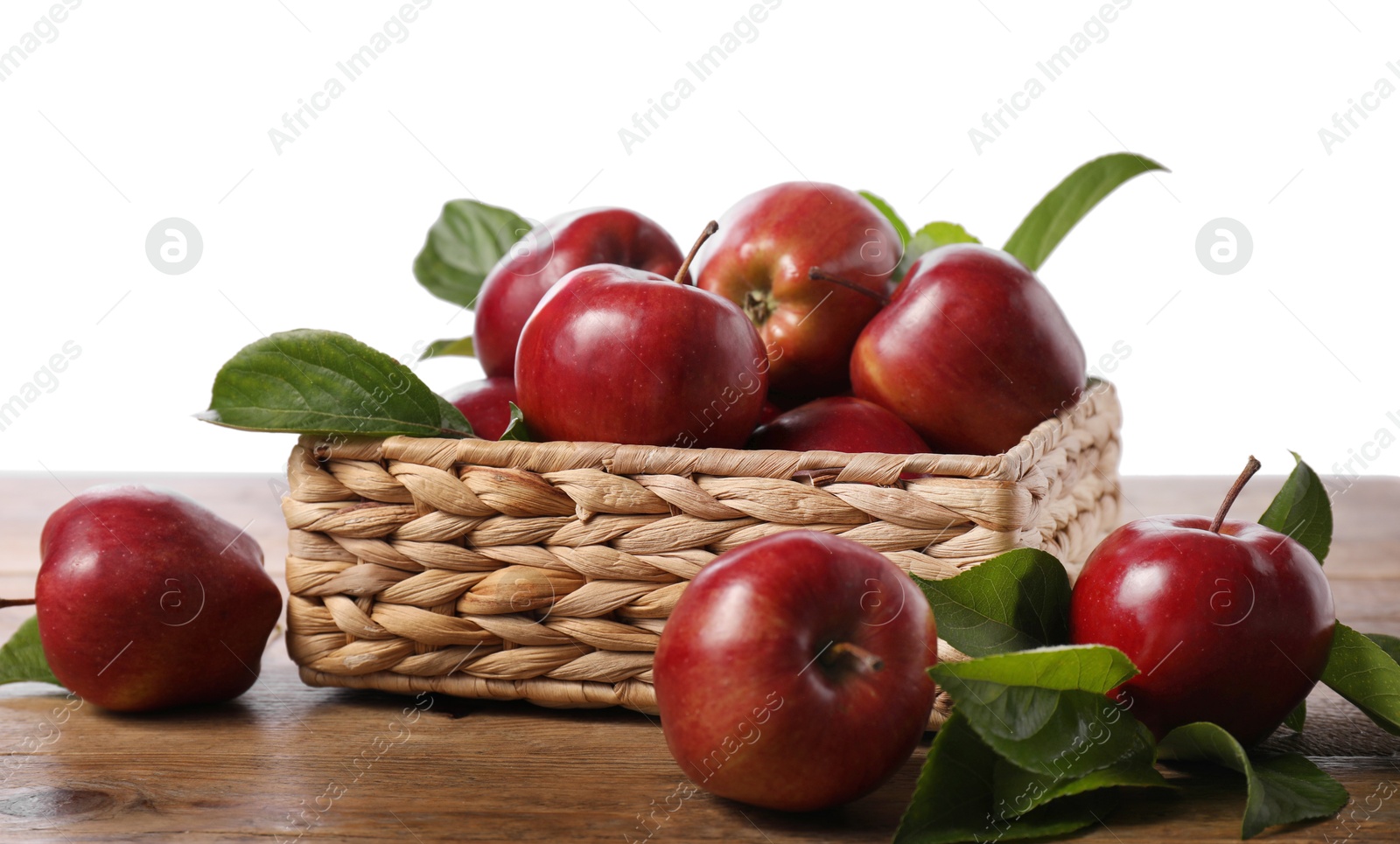 Photo of Fresh red apples and leaves in basket on wooden table against white background