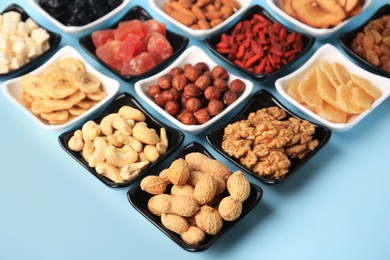Photo of Bowls with dried fruits and nuts on light blue background
