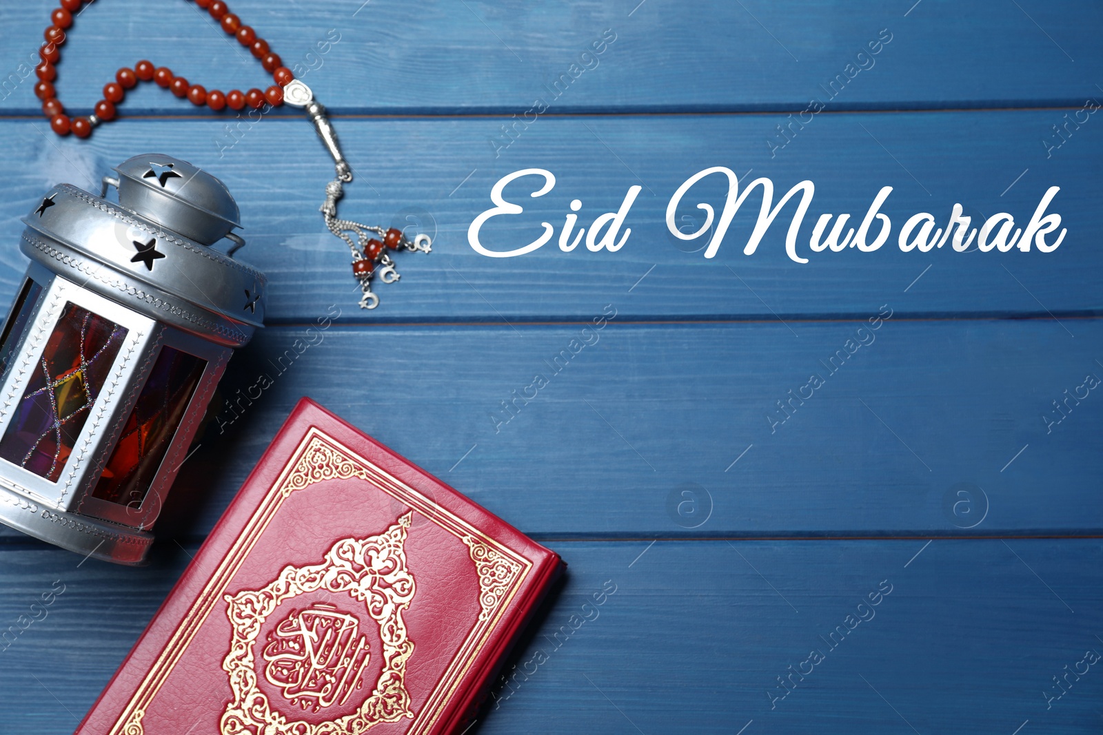 Image of Eid Mubarak greeting card. Arabic lantern, Quran and misbaha on blue wooden background, flat lay