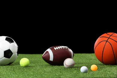 Photo of Many different sports balls on green grass against black background, space for text