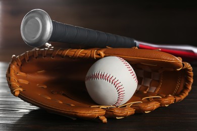 Baseball glove, bat and ball on wooden table, closeup