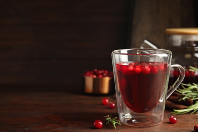 Photo of Tasty hot cranberry tea on wooden table. Space for text