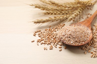 Photo of Wheat bran, kernels and spikelets on wooden table, closeup. Space for text