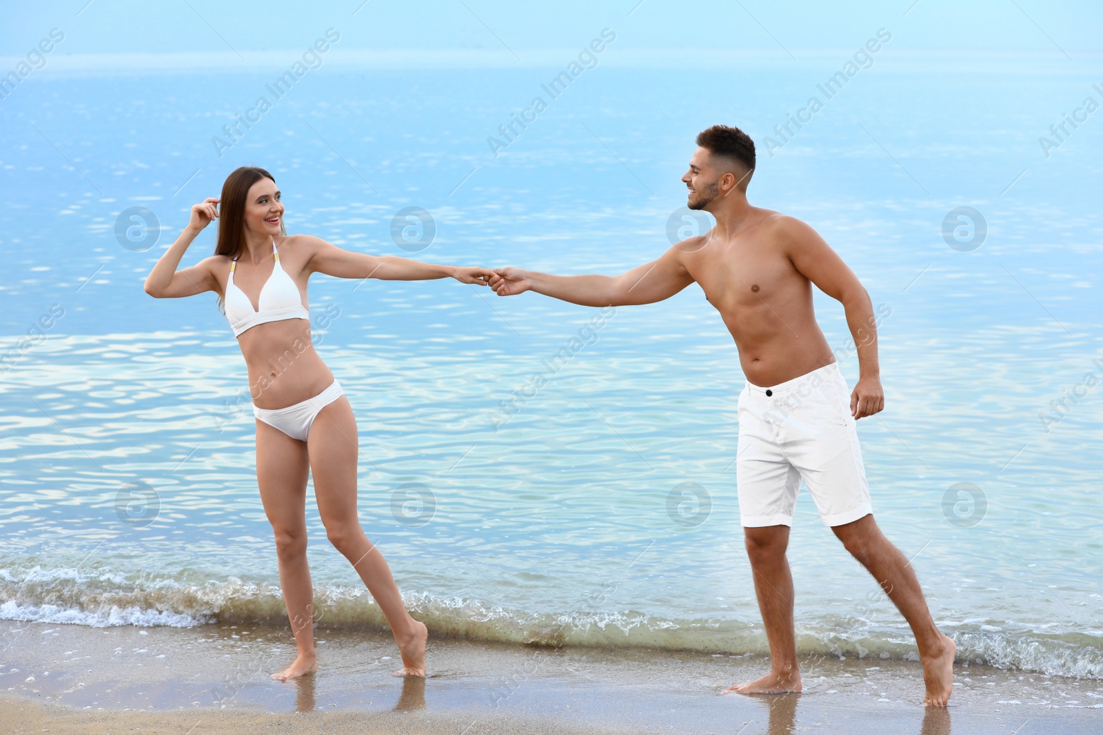 Photo of Young woman in bikini with her boyfriend on beach. Lovely couple