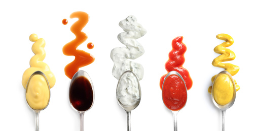 Image of Set of spoons with different delicious sauces on white background, top view