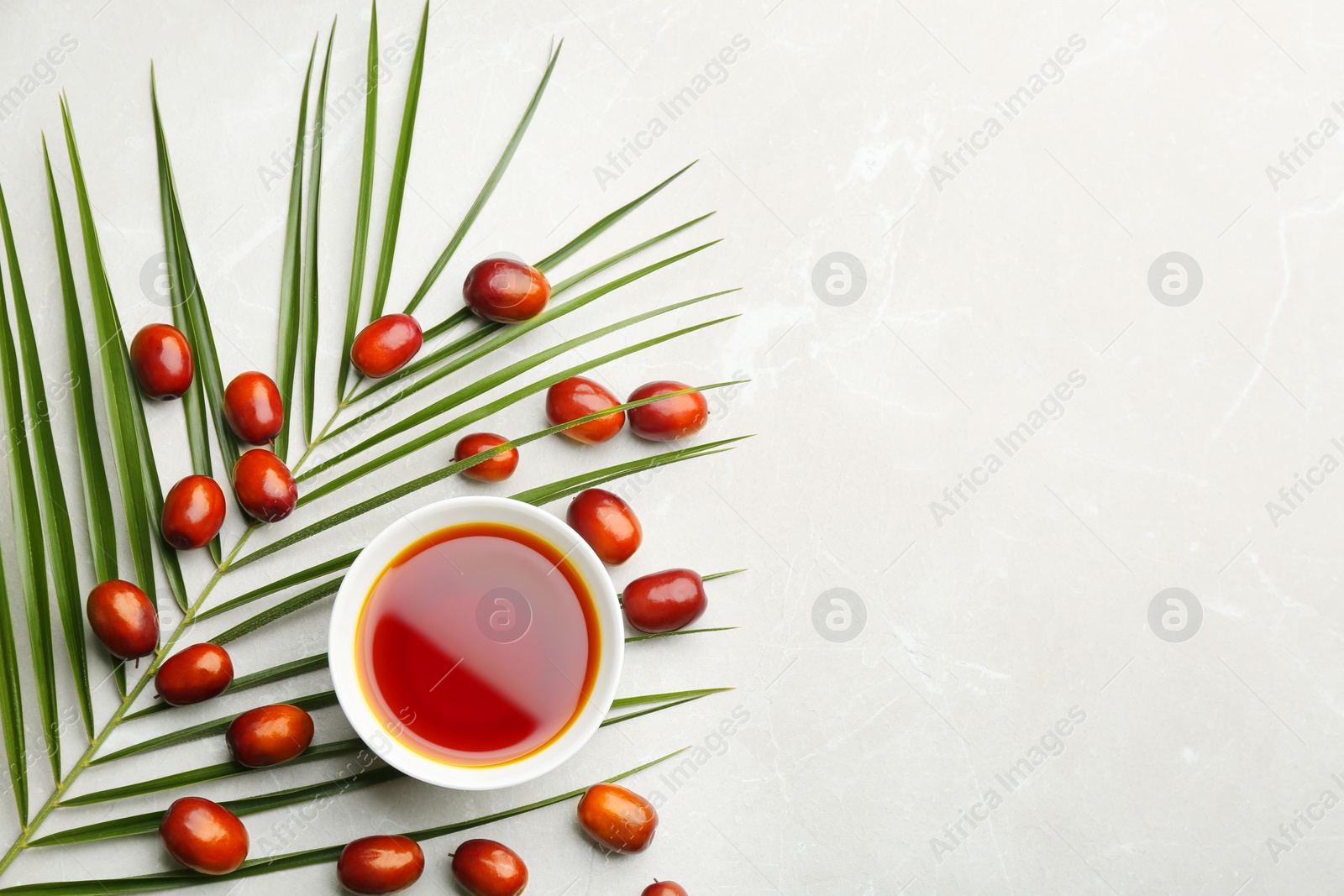 Photo of Palm oil in bowl, tropical leaf and fruits on light table, flat lay. Space for text