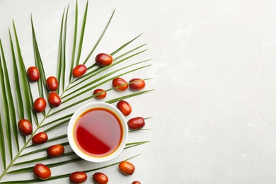 Palm oil in bowl, tropical leaf and fruits on light table, flat lay. Space for text