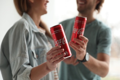 MYKOLAIV, UKRAINE - NOVEMBER 28, 2018: Young couple with Coca-Cola cans indoors, closeup