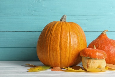 Photo of Different pumpkins on table against wooden wall. Autumn holidays