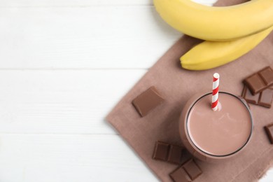 Photo of Yummy chocolate milk and fresh ingredients on white wooden table, flat lay. Space for text