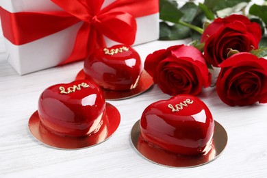 St. Valentine's Day. Delicious heart shaped cakes, roses and gift on white wooden table