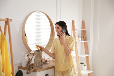 Photo of Young woman talking on phone at home in morning