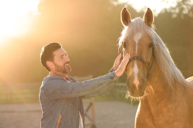 Photo of Man with adorable horse outdoors on sunny day. Lovely domesticated pet