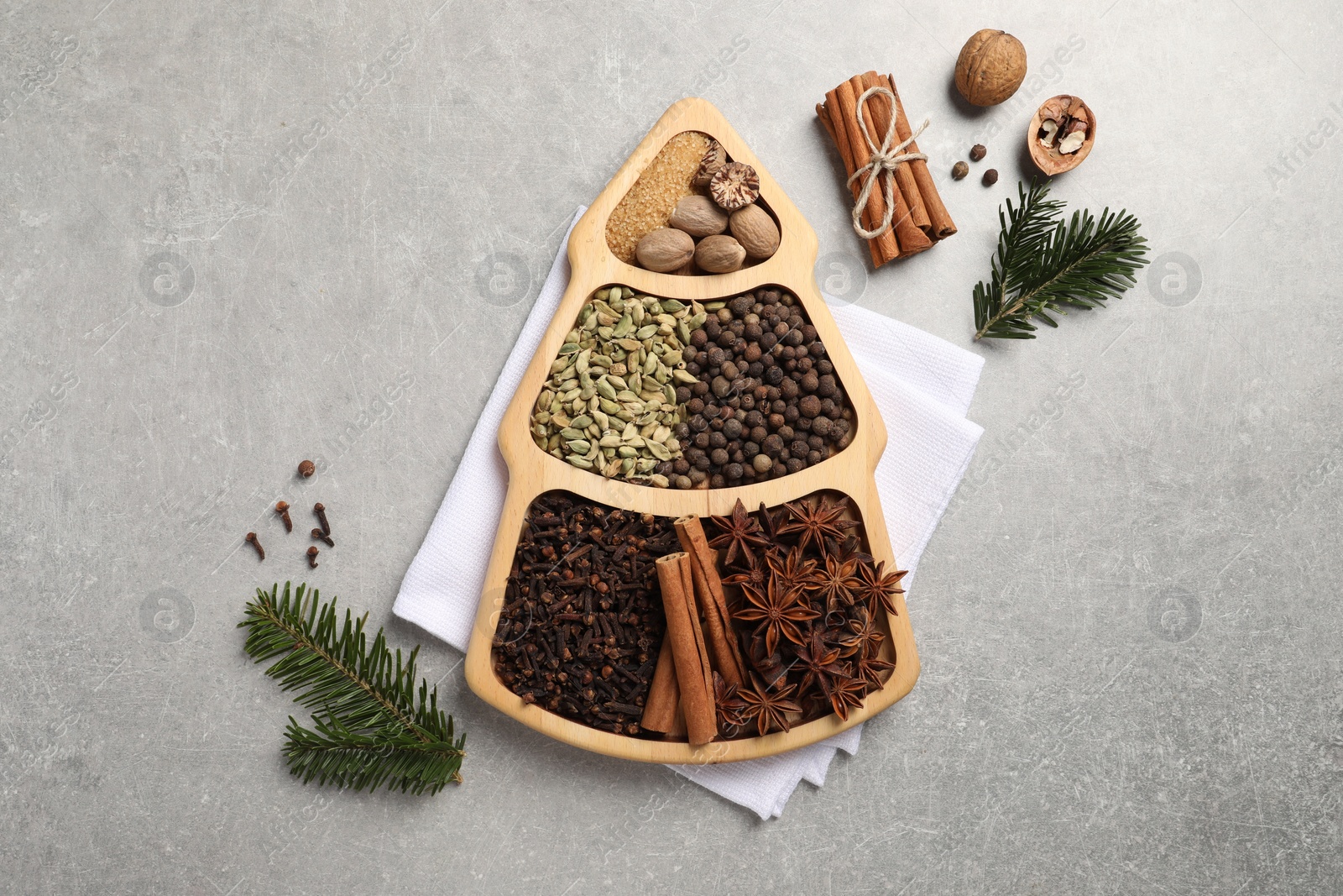 Photo of Different spices, nuts and fir branches on gray textured table, flat lay