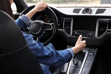 Woman using gear stick while driving her car, closeup