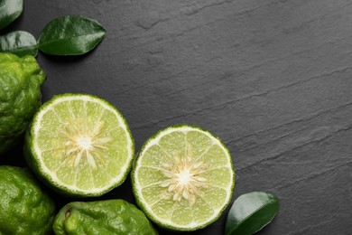 Photo of Fresh ripe bergamot fruits with green leaves on black table, flat lay. Space for text