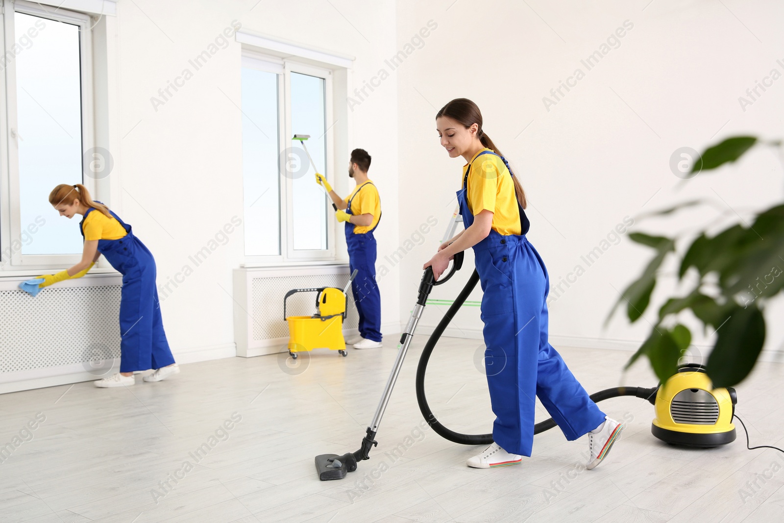 Photo of Team of professional janitors in uniforms cleaning room