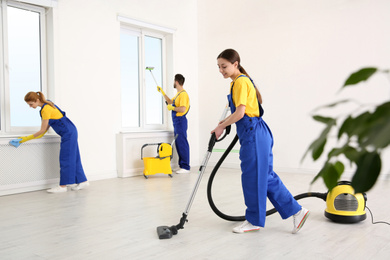 Photo of Team of professional janitors in uniforms cleaning room